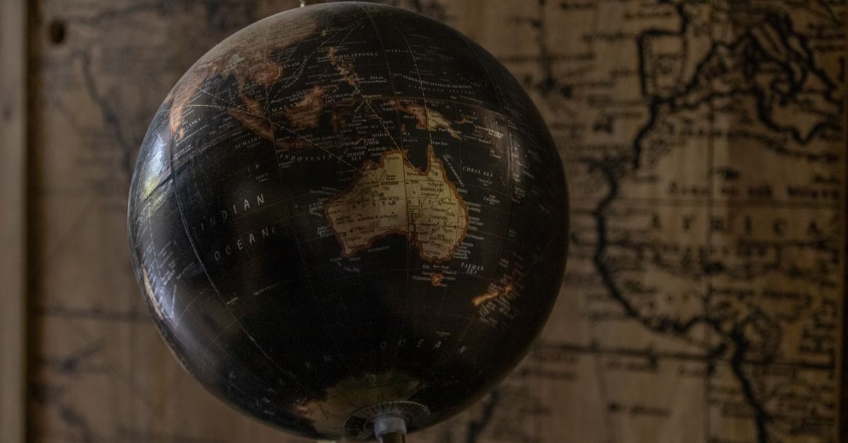 A vintage globe showcases Australia with a sepia world map in the background, offering a classic exploration theme.